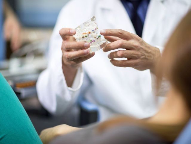 dentista explicando a paciente con molde de dientes